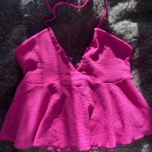 Rosa ärmlös topp - Rosa topp med smala axelband som knyts i nacken, v-ringning samt öppen rygg