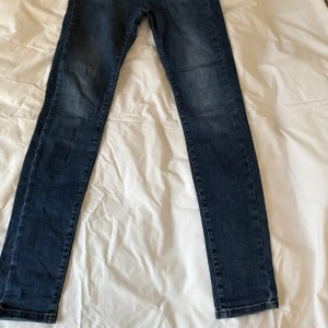 Blå stella jeans House of Lola - Snygga blå jeansbyxor med en klassisk design. De har en knapp och dragkedja framtill samt fem fickor. Materialet är en blandning av bomull, polyester och elastan vilket gör att de är mjuka och elastiska. Längde är ner till hälen på mig som är 1,63 cm. Midjan är hög. De är i fint skick.