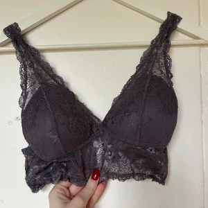 Grå spets bralette från Gina Tricot - Säljer en elegant grå spets bralette från Gina Tricot. Den har ett vackert blommigt spetsmönster och är perfekt för en stilren look. Braletten är bekväm och ger ett fint stöd.