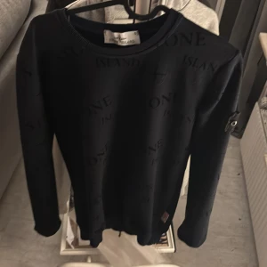 Mörkblå tröja från Stone Island - Säljer en snygg mörkblå tröja från Stone Island med diskret mönster och det ikoniska märket på ärmen. Tröjan har långa ärmar och en rund halsringning. Perfekt för en stilren look.