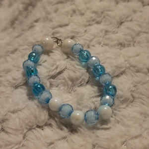 Blått och vitt armband med pärlor - Charmigt armband med pärlor i olika nyanser av blått och vitt. Pärlorna är runda och har en glansig yta som ger en fin lyster. Perfekt för att lägga till en färgklick till din outfit.