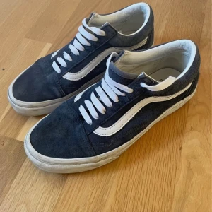 Svarta sneakers från Vans - Snygga svarta Vans sneakers med vit sula och klassisk vit sidostrimma. Skorna har snörning och en bekväm passform, perfekt för vardagsbruk. Den bruna gummisulan ger bra grepp och hållbarhet.