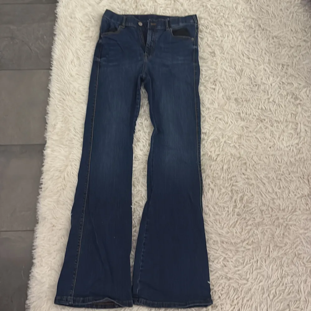 Snygga blå bootcut jeans med klassisk femficksdesign och knappgylf. Perfekta för en avslappnad stil med en touch av retro. Passar bra till både sneakers och stövlar.. Farkut & Housut.