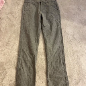 Grå byxor från East West - Snygga grå byxor från East West med en klassisk design. Byxorna har en rak passform och är tillverkade i ett bekvämt material. De har knappar bak och en stilren look som passar perfekt för olika tillfällen.