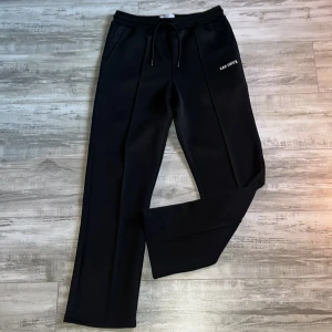 Svarta byxor från Les Deux - Snygga svarta byxor från Les Deux med dragsko i midjan och raka ben. Perfekta för en stilren look. Byxorna har en diskret logga på sidan och är gjorda i ett bekvämt material. Använt dom två gånger för det var inte riktigt min stil