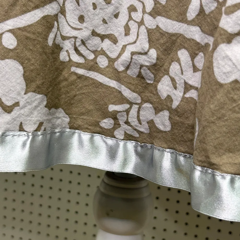 Charmig midi kjol med vitt blommönster och en glansig satin kant. Kjolen har en utsvängd form som ger en fin siluett. Perfekt för en somrig look!. Hameet.