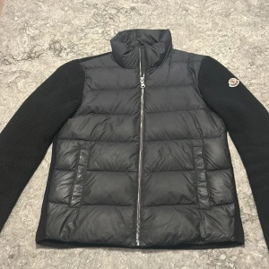 Svart Cardigan från Moncler - Säljer en snygg svart cardigan från Moncler med stickade ärmar och dragkedja framtill. Jackan har en quiltad design och Moncler-logga på armen. Jackan är använt i cirka en månad Inga defekter. Pris kan diskuteras. Hör av er om ni har några frågor. Jackan är köpt från monclear för ungefär 7000kr.