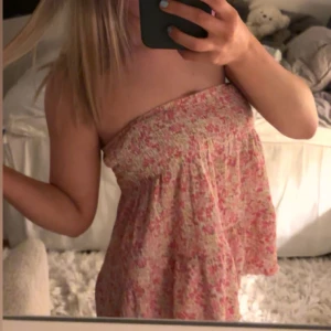 Blommig axelbandslös topp - Söt axelbandslös topp med blommigt mönster i rosa och vit. Perfekt för varma sommardagar med sin lätta och luftiga design.