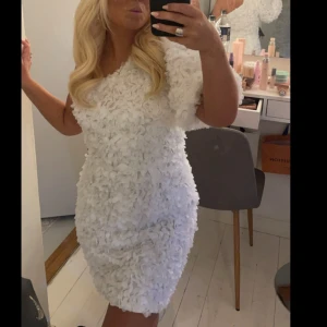 Vit klänning med blommig textur - Säljer en unik vit klänning med en fantastisk blommig textur. Klänningen är axelbandslös och har en tight passform som framhäver figuren. Perfekt för speciella tillfällen när du vill sticka ut. Klänningen har bara en arm och är one shoulder och den är använd en gång❤️