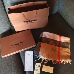Burberry halsduk - Inte använd så mycket bra skick, är äkta och alla tillbehör som kvitto följer med. Pristet är inte fäst kan få för billigare vid snabb affär eller utan tillbehörna