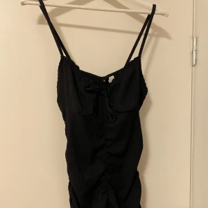 Svart ruched klänning - Svart ruched klänning från HM, söt rosett, ger väldigt fin form