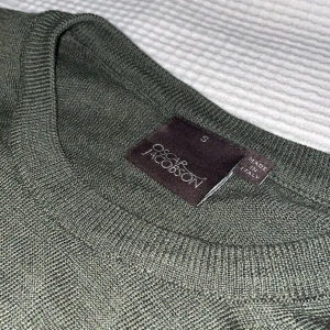 Oscar Jakobson tröja - Helt ny och oanvänd tröja från Oscar Jakobson. Materialet på tröjan är merinoull så den är extremt skön. Köptes i Stockholm på volt. Finns inga tecken på användning och passar bra till mycket. Köptes för 1399kr men säljer eftersom den inte används.