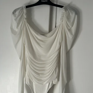 Vit blus/body - En vit body storlek L. Jätte stretchigt matrial. Genomskinlig på armarna men dubbelt matrial över bröst och rygg. Tre knappar 