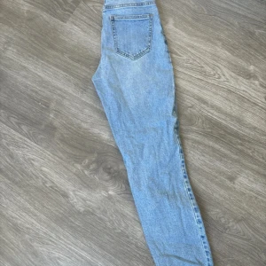 Blå jeansbyxor - Säljer ett par klassiska blå jeansbyxor i bra skick. De har en normal passform och är perfekta för vardagsbruk. Byxorna har en bakficka och är i en ljusblå tvätt som passar till det mesta. Perfekta för både vår och sommar!