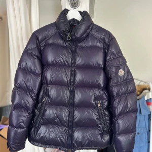 Moncler Maya  - Storlek 4/L 7/10 finns små siltage typ som på armen och så dant. Det går att fixa hos en skräddare men själv har jag tyvärr inte haft tid. Samt att medaljongen har bytes ut!  Den är äkta men det är också en äldre modell!  Bilder/Frågor kom PM! 