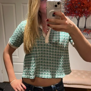 Grön och vit mönstrad topp med lite krage  - Säljer en superfin grön och vit mönstrad polotopp. Den är croppad och har korta ärmar. Toppen har en snygg krage och knappar framtill. Passar både till jeans och kjol. 💚🤍säljer den för att den tyvärr inte kommer till användning!💚🤍