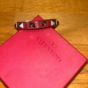 Valentino armband - Säljer nu ett valentino armband i färgen vinröd. Armbandet är i relativt bra skick. Det är mest baksidan av armbandet (bild 3) där skicket inte är riktigt lika bra då armbandet är rätt så välanvänt, det är dock inget som syns när du har det på dig.