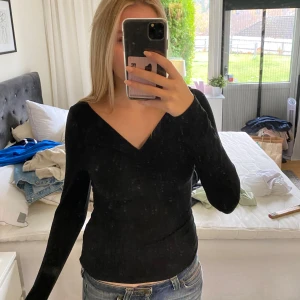 Svart ribbad topp från NA-KD - Säljer en snygg svart ribbad topp från NA-KD. Den har en v-ringad design med långa ärmar och en smickrande passform. Perfekt för både vardag och fest! 🖤