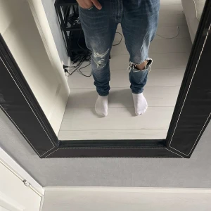 Tiger of sweden jeans - Säljer ett par snygga blå jeans med coola slitningar på framsidan. De har en slim passform och är perfekta för en avslappnad stil. Jeansen är i bra skick och har en klassisk femficksdesign. Perfekta för både vardag och fest!32/32