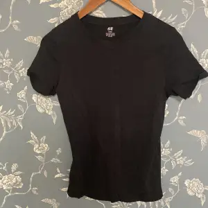 Säljer en svart basic t-shirt från H&M i storlek EUR 146/152. Den är gjord av 100% bomull och är superbekväm. Perfekt för vardagsbruk och kan matchas med nästan vad som helst. Kortärmad och i nyskick! Köptes för 200kr