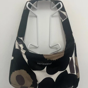 Marimekko axelväska - Klassisk svart och vit axelväska från Marimekko. Mycket bra skick då den aldrig är använd.  Bredd 28cm Höjd 17cm