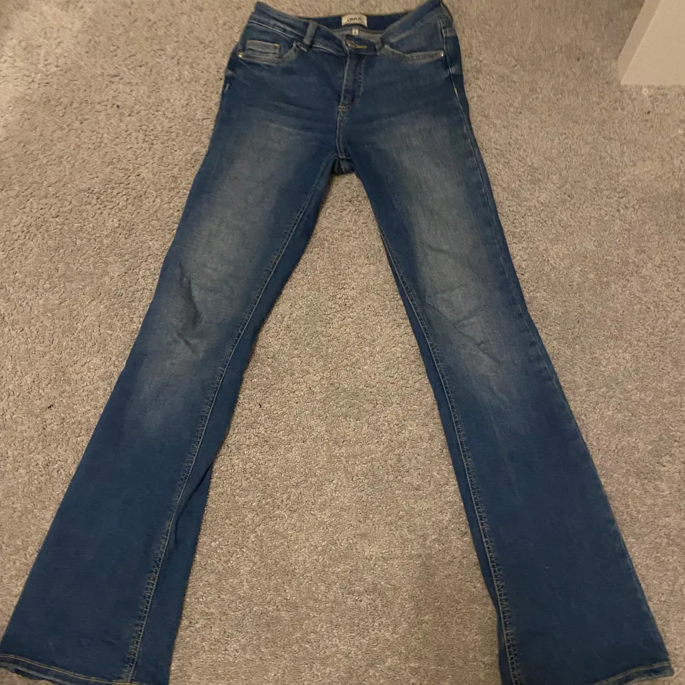 Säljer ett par snygga blå jeans från ONLY i storlek S. De har en klassisk bootcut passform. Jeansen är i bra skick och är midwaist. Längden passar mig som är 170 cm. Jeans & Byxor.