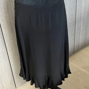 Svart långkjol - Snygg svart långkjol i mjukt material, perfekt för både vardag och fest. Kjolen har en elegant och flytande passform som ger en fin siluett. Den är enkel att matcha med olika toppar och accessoarer för en komplett look.