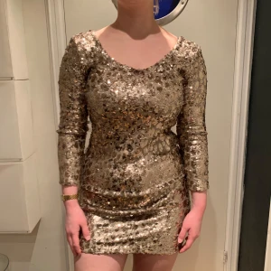 Designer klänning från Valerie Fest Klänning  i guld paljetter  - Cool fest klänning i guld paljetter med stretch. Designer är Valerie stl38. Skicket är som att den är ny, endast använd fåtal tillfällen. Passa på!