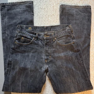 Grå jeans från Lee - Säljer ett par grå vintage jeans från Lee i storlek 30-32. De är tillverkade i 100% bomull och har en klassisk femficksdesign med knappar. Långa raka ben som är lätt utsvängda i slutet. Midjemått 38 cm, innebenslängd 79 cm 