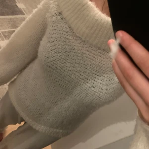 Vit stickad tröja med bred krage - Mysig vit stickad tröja med en bred och fluffig krage. Perfekt för kyliga dagar när du vill känna dig både varm och stilren. Tröjan har en lös passform och långa ärmar, vilket gör den superbekväm att bära. Passar perfekt till både jeans och kjol!