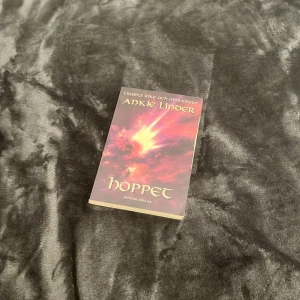 Hoppet - Boken 'Hoppet' av Ankie Linder är en del av serien 'Ljusets rike och mörkrets'. Omslaget har en dramatisk design med eldiga färger som ger en känsla av mystik och äventyr. Perfekt för dig som gillar fantasy och spännande berättelser.