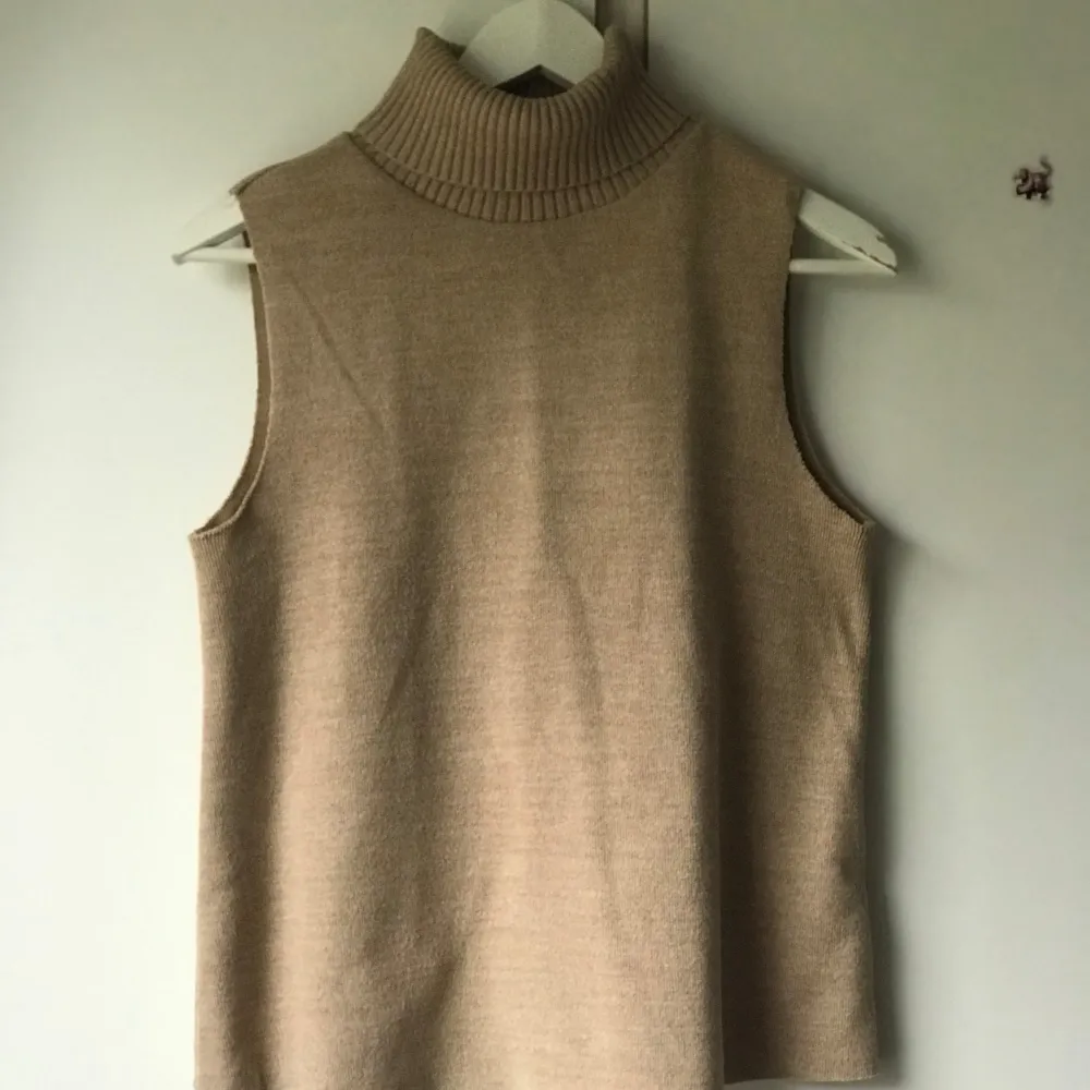 Säljer en stilren beige ärmlös polotröja i mjukt material. Perfekt för lager-på-lager under hösten eller våren. Den har en hög krage som ger en elegant touch. Passar både till vardags och lite finare tillfällen. 🧥✨. Tröjor & Koftor.