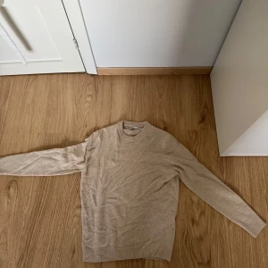 Beige tröja från Zara - Säljer en stilren beige tröja från Zara i storlek M. Den är supermjuk och perfekt för både höst och vinter. Tröjan har långa ärmar och en klassisk rund halsringning. Passar perfekt till både jeans och kjol för en avslappnad look.