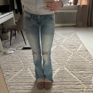 Ljusa bootcut jeans - Snygga ljusa bootcut jeans från Nelly med slitna detaljer på knäna. Nersydda i benen, långa  på mig som är 174. Mycket bra skick använda fåtal gånger.