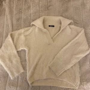 Beige stickad tröja från Gina Tricot - Mysig beige stickad tröja från Gina Tricot med en bred krage och långa ärmar. Perfekt för kyliga dagar med sin mjuka och bekväma design. Passar utmärkt till både jeans och kjol. Jättesöt då den är lite fluffig 💗Modellen säljs inte längre av gina 💕
