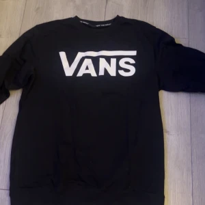 Svart sweatshirt från Vans - Säljer en svart sweatshirt från Vans med deras logga i vitt på framsidan.  Den är tillverkad i ett mjukt material som gör den bekväm att bära. Aldrig använd och är i nyskick. Storlek M