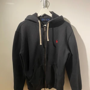 Svart zip hoodie från Polo Ralph Lauren - Snygg svart hoodie från Polo Ralph Lauren. ✨Skick 9/10✨ Perfekt för alla tillfällen och har väldigt bra passform!
