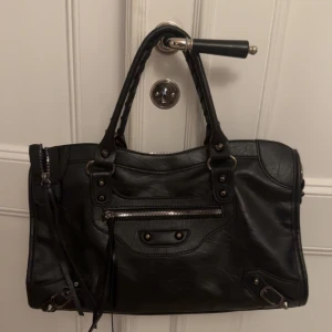 Svart skinnväska med dragkedja - Snygg svart skinnväska med dragkedja och detaljerade sömmar. Väskan har två handtag och en praktisk dragkedja framtill. Perfekt storlek då den rymmer dator, böcker etc!! Måtten: 39x24 💗Jag kan gå ner lite i pris  vid snabb affär💗😇väldigt eftertraktad