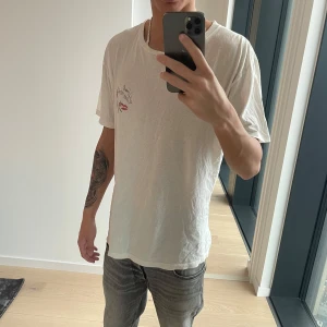 Saint Laurent T-shirt  - Vit saint Laurent T-shirt med tryck på bröstet, storlek S fits M. Jag är 187 och väger ca 65kg.