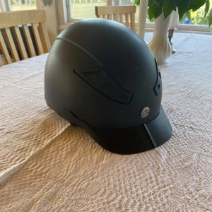 Svart ridhjälm från Back on Track - Säljer en stilren svart ridhjälm från Back on Track, modell EQ3 Lynx. Storlek 54-58/M, regleras bak. Fint skick