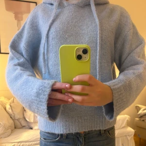 Ljusblå stickad hoodie - Mysig ljusblå stickad hoodie med långa ärmar och justerbar huva. Perfekt för kyliga dagar när du vill vara både bekväm och stilren. Passar bra till jeans eller leggings.