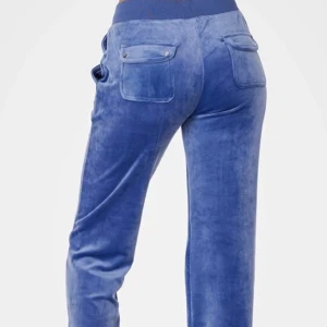 Blå velourbyxor med snörning - Snygga blå velourbyxor med hög midja och snörning i midjan. Byxorna har fickor både fram och bak, vilket ger en avslappnad och bekväm stil. Perfekta för en chill dag hemma eller en avslappnad utflykt. Det finns en fläck, men har inte testat att ta bort. Skriv till mig om ni vill ha flera bilder!