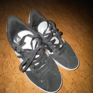 Svarta sneakers från Adidas - Snygga svarta sneakers från Adidas med vita ränder och snörning. Perfekta för en avslappnad stil. ( ny pris 900 o säljer för 500 för dom är knappt använda!kr