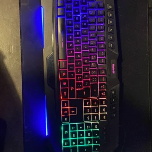 Gamingtangentbord med RGB-belysning - Snyggt gamingtangentbord med RGB-belysning som skiftar i regnbågens färger. Tangentbordet har en robust design med tydliga, upplysta tangenter för optimal spelupplevelse. Perfekt för gamers som vill ha stil och funktionalitet. Bara för 150
