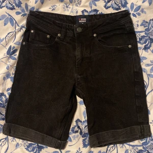 Svarta jeansshorts från Denim Project - Snygga svarta jeansshorts från Denim Project med klassisk femficksdesign och uppvikta benslut. Perfekta för en avslappnad stil.