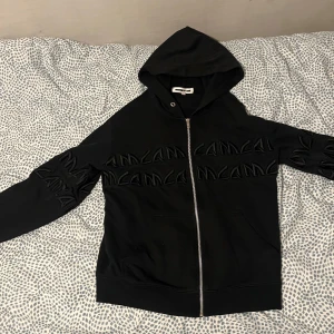 Svart huvtröja med dragkedja - Snygg svart zip upmed dragkedja och broderad textdetalj på bröstet. .Y2K zip up som får många komplimanger. Pris kan diskuteras