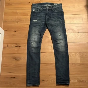 Mörkblå jeans från Diesel - Snygga mörkblå slim fit jeans från Diesel med slitna detaljer oJeansen har en knappgylf och är perfekta för en avslappnad stil. Märket är synligt på bakfickan. Storlek 28/32. Köpta här på Plick men var för små så säljer dom för billigare pris. Här gärna av er om ni har några frågor o funderingar:)