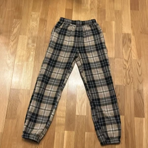 Rutig pjamasbyxor från Shein - Säljer ett par bekväma och stiliga rutiga byxor från Shein. Byxorna har en elastisk midja och är i en beige och svart färgkombination. Perfekta för en avslappnad look.❤️