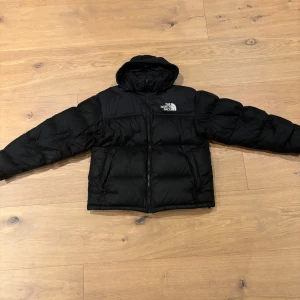Svart dunjacka från The North Face - Säljer en svart dunjacka från The North Face. Jackan har en pufferdesign med dragkedja och huva. Perfekt för kalla dagar. Kan eventuellt gå ner lite i pris 
