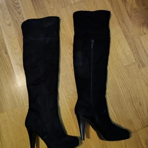 Svarta stövlar med klack - Eleganta svarta stövlar i mocka med hög klack och dragkedja på sidan. Perfekta för en stilren look.